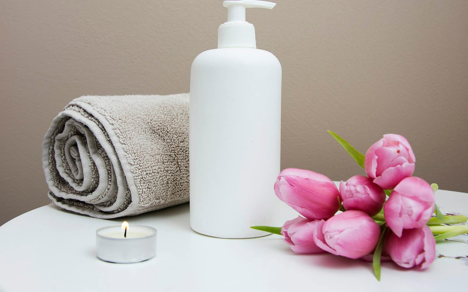 A serene home spa setup with massage oil, a towel and a candle